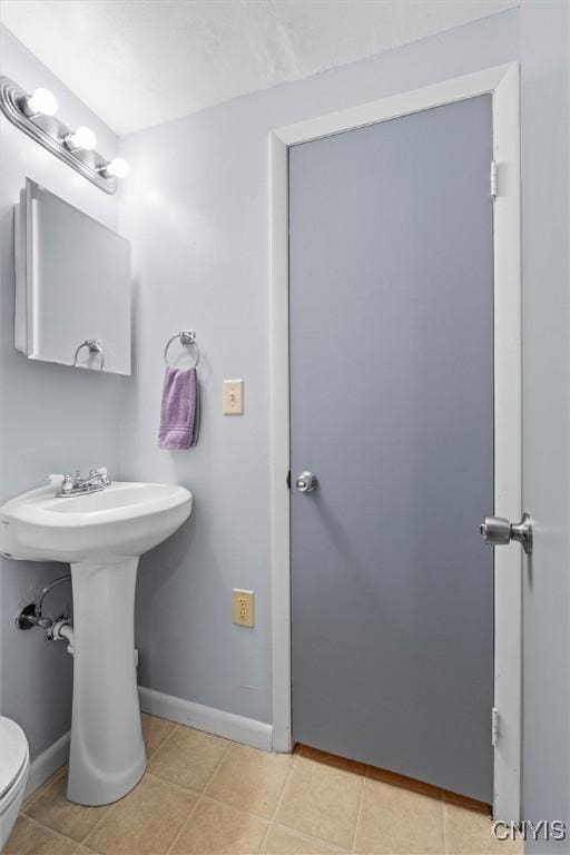 bathroom with tile patterned floors, toilet, and baseboards