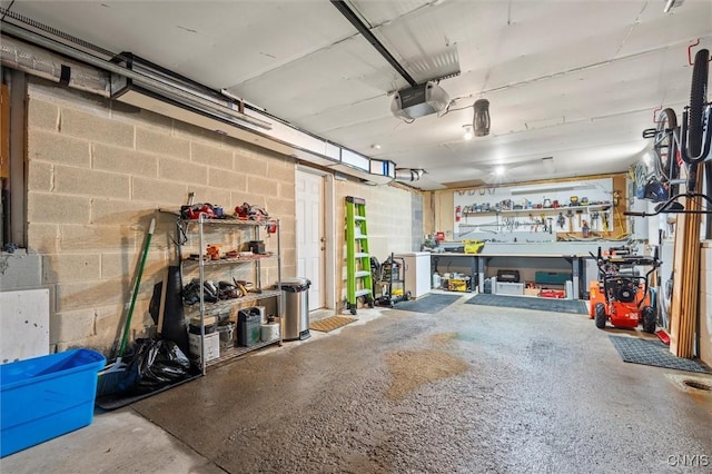 garage with concrete block wall, a workshop area, and a garage door opener