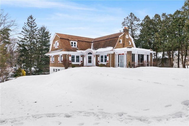 view of front of home with a garage, a chimney, and a gambrel roof