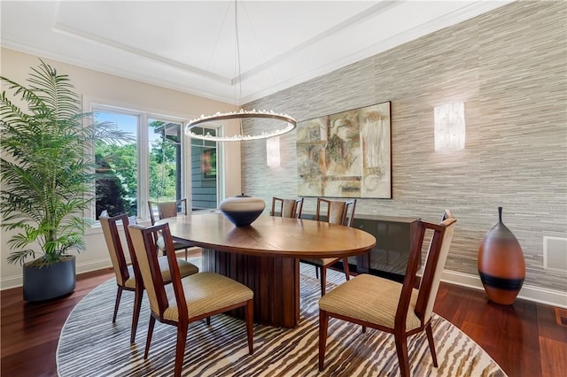 dining room with a raised ceiling, baseboards, and wood finished floors