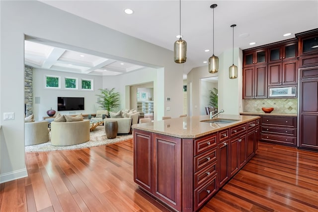 kitchen featuring dark brown cabinets, white microwave, a sink, and dark wood finished floors