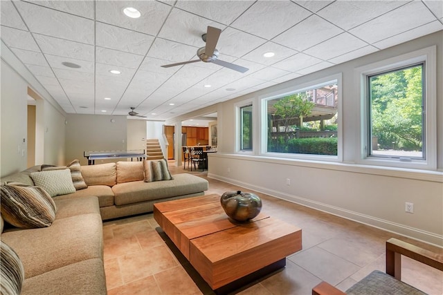 living room featuring light tile patterned floors, a drop ceiling, recessed lighting, a ceiling fan, and baseboards