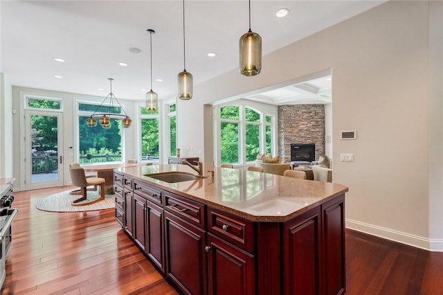 kitchen with coffered ceiling, a sink, beam ceiling, reddish brown cabinets, and dark wood finished floors