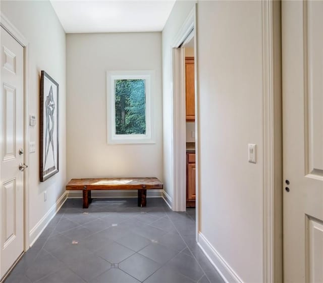 corridor featuring dark tile patterned flooring and baseboards