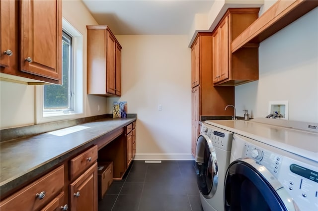 washroom with dark tile patterned floors, a sink, baseboards, independent washer and dryer, and cabinet space