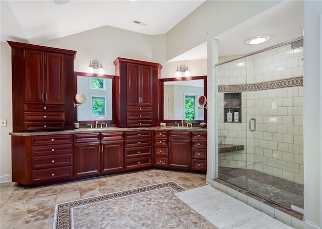 bathroom featuring lofted ceiling, a shower stall, double vanity, and a sink