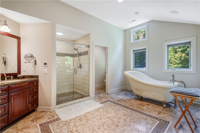 bathroom with a stall shower, baseboards, vaulted ceiling, and vanity