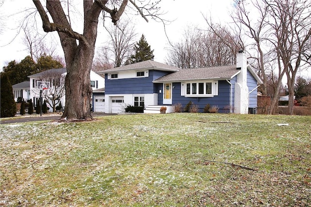 tri-level home with a front yard, a chimney, and an attached garage