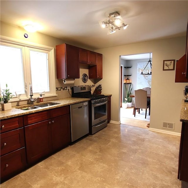 kitchen with a notable chandelier, baseboards, stainless steel appliances, and a sink