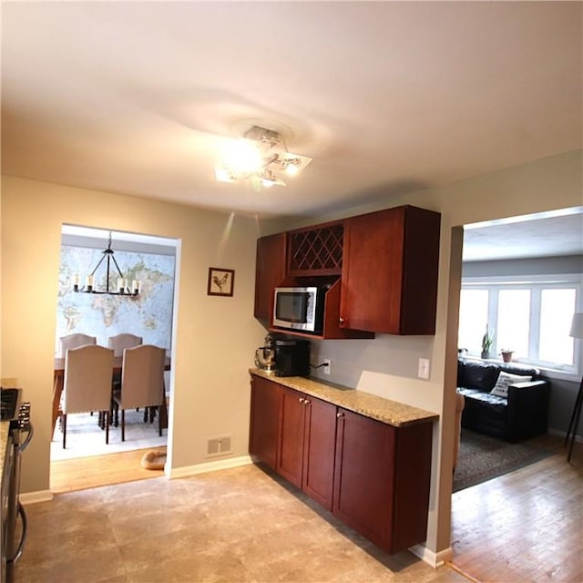 kitchen featuring a notable chandelier, stainless steel appliances, visible vents, baseboards, and light stone countertops