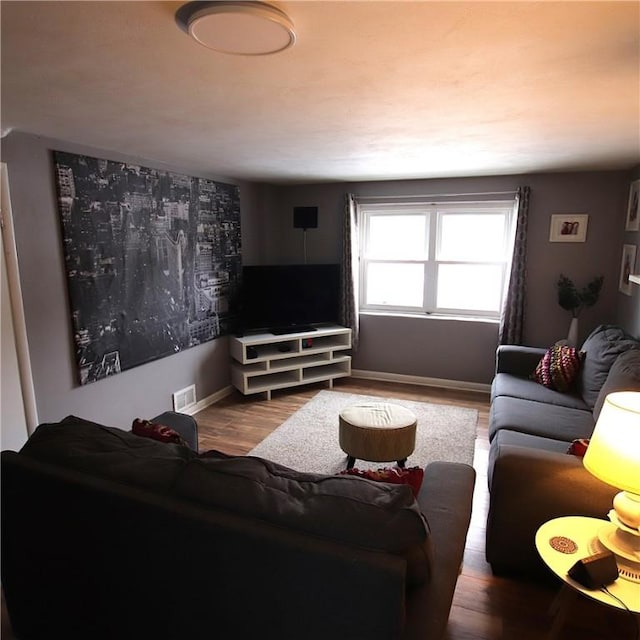 living area featuring wood finished floors, visible vents, and baseboards