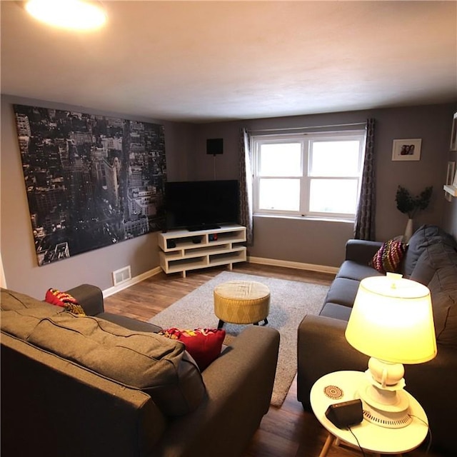 living area with wood finished floors, visible vents, and baseboards