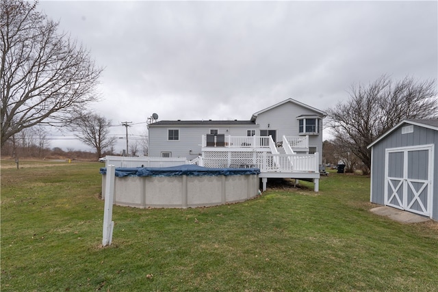 back of house featuring a covered pool, a lawn, a deck, an outbuilding, and a storage unit