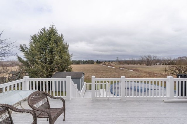 wooden deck featuring a rural view, an outdoor structure, and a storage shed