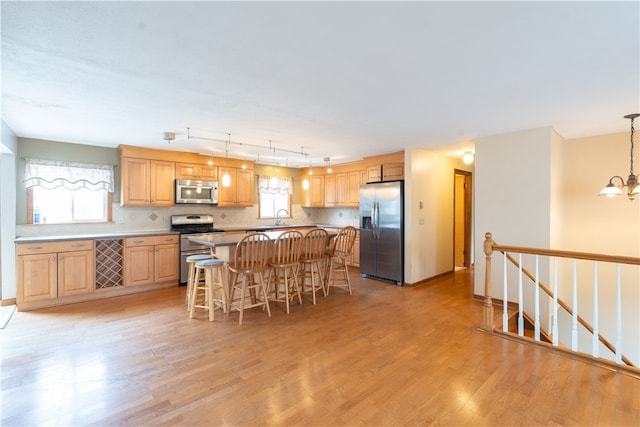 kitchen featuring a chandelier, appliances with stainless steel finishes, a breakfast bar, and a wealth of natural light