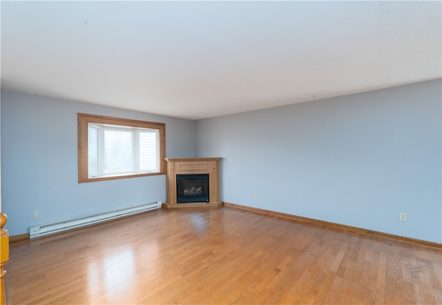 unfurnished living room with a glass covered fireplace, a baseboard heating unit, baseboards, and light wood-style flooring