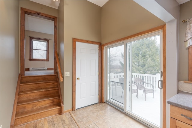 doorway to outside with light tile patterned floors, baseboard heating, and stairway