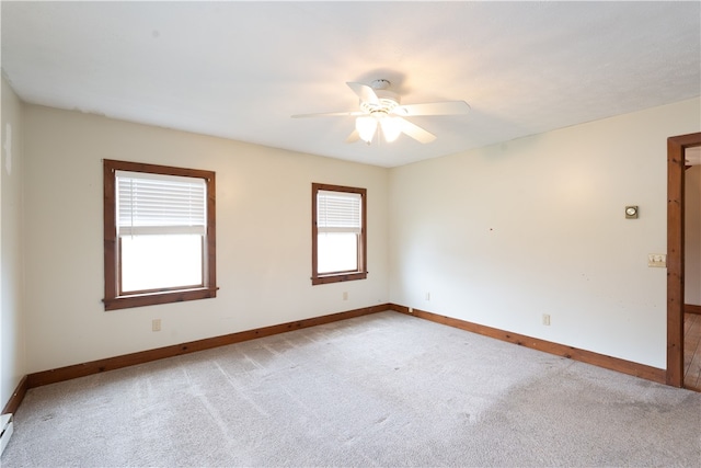 empty room with light colored carpet, a baseboard radiator, baseboards, and ceiling fan