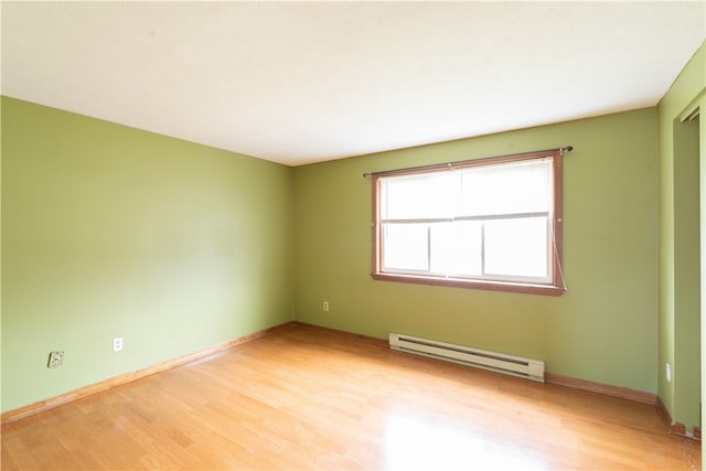 empty room featuring light wood-style floors, baseboards, and baseboard heating