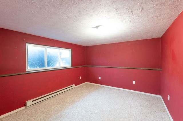 carpeted empty room featuring a baseboard heating unit, baseboards, and a textured ceiling