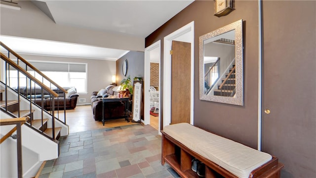 hallway featuring stone finish flooring, baseboards, and stairs