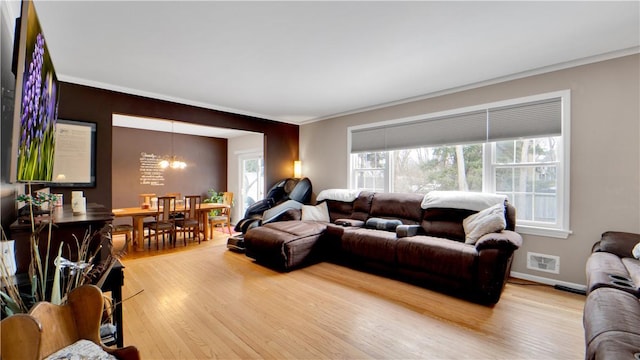 living room with a notable chandelier, visible vents, ornamental molding, wood finished floors, and baseboards