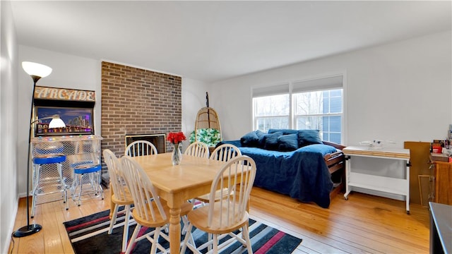 dining area featuring a brick fireplace and wood-type flooring