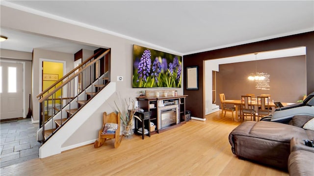 living room with a chandelier, wood finished floors, baseboards, and stairs