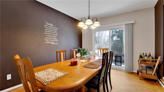 dining room with light wood-type flooring, baseboards, and an inviting chandelier