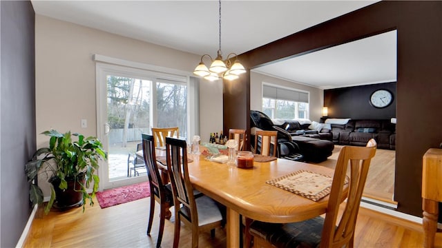 dining space featuring light wood finished floors, beam ceiling, and an inviting chandelier