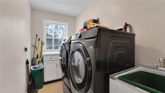 washroom with washing machine and dryer, cabinet space, and a sink