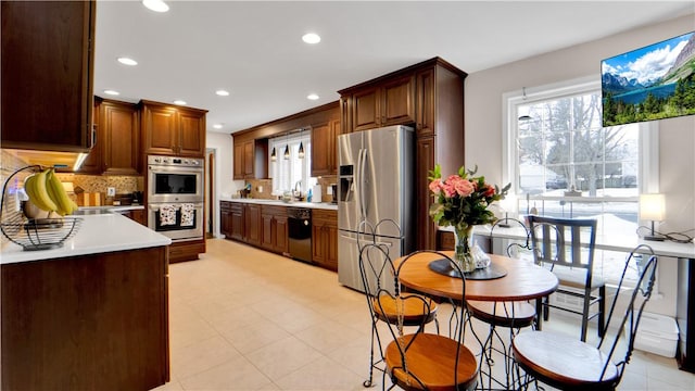 kitchen featuring stainless steel appliances, recessed lighting, light countertops, decorative backsplash, and a sink