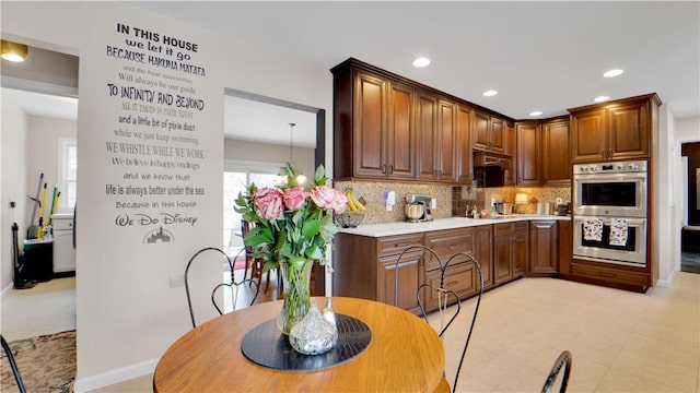 kitchen featuring baseboards, light countertops, stainless steel double oven, backsplash, and recessed lighting