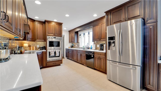 kitchen with tasteful backsplash, appliances with stainless steel finishes, light countertops, a sink, and recessed lighting