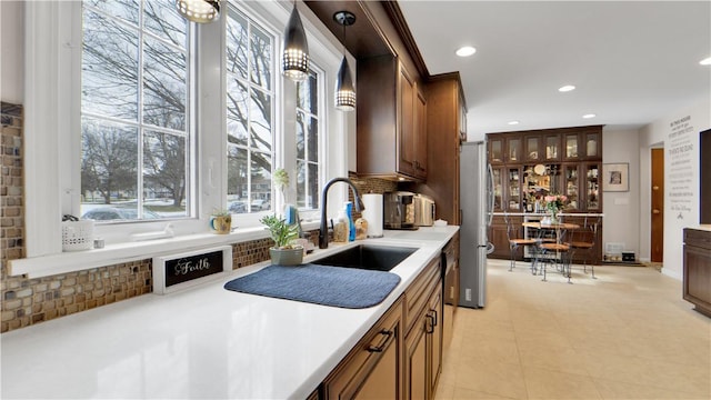 kitchen featuring tasteful backsplash, freestanding refrigerator, light countertops, a sink, and recessed lighting