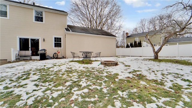 snow covered house with fence and a fire pit