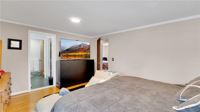 bedroom featuring baseboards, ensuite bath, wood finished floors, and crown molding