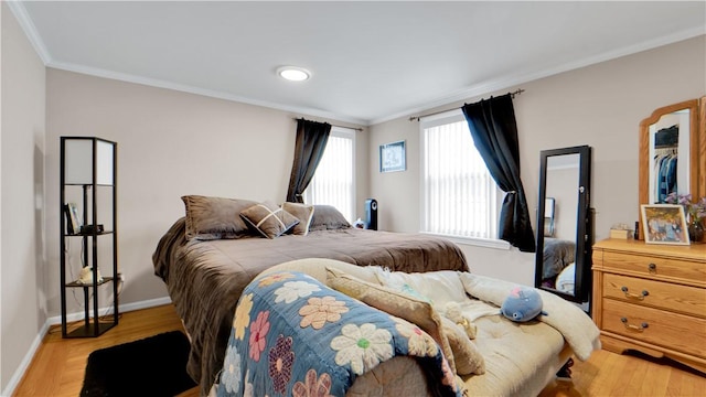 bedroom featuring light wood finished floors, baseboards, and crown molding