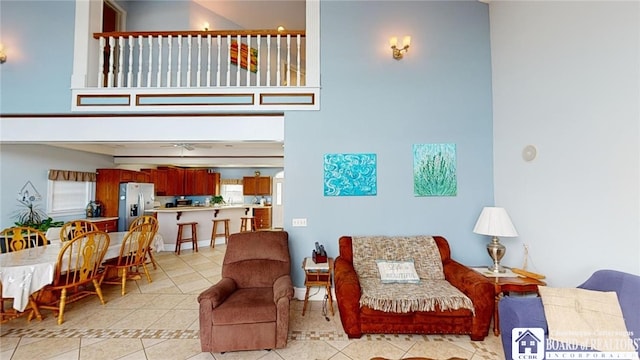 living area featuring light tile patterned floors, a towering ceiling, and baseboards