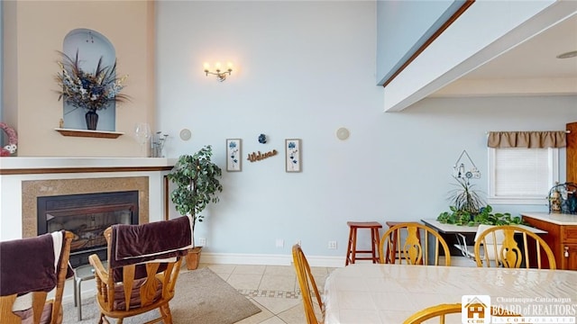 dining room with light tile patterned floors, baseboards, and a glass covered fireplace