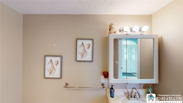 bathroom with a textured ceiling and a sink