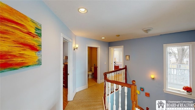 hallway featuring light carpet, baseboards, an upstairs landing, and recessed lighting