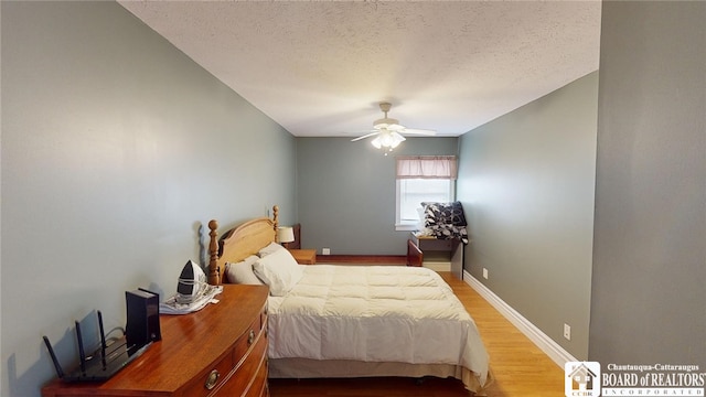 bedroom featuring a textured ceiling, ceiling fan, wood finished floors, and baseboards