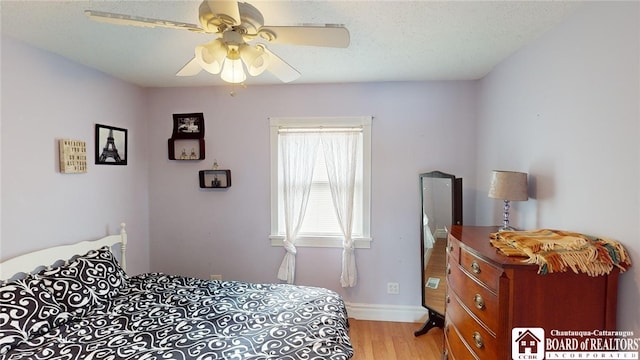 bedroom with baseboards, light wood-style flooring, a ceiling fan, and a textured ceiling