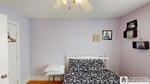 bedroom with ceiling fan, baseboards, and wood finished floors