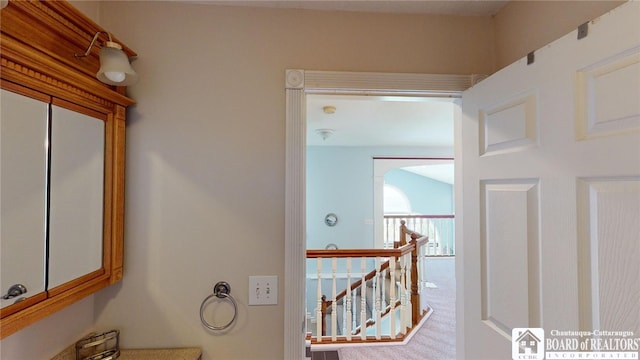 hall with carpet flooring and an upstairs landing