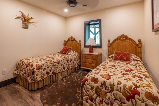 bedroom with visible vents, baseboards, and wood finished floors