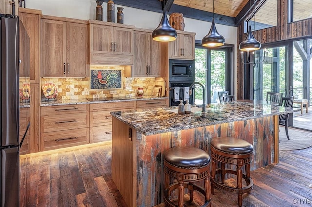 kitchen with built in microwave, dark wood finished floors, a sink, and backsplash