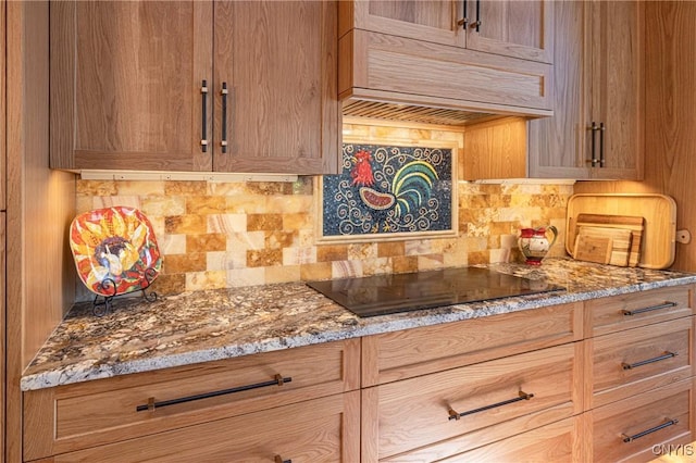 kitchen featuring light stone countertops, custom exhaust hood, black electric cooktop, and decorative backsplash