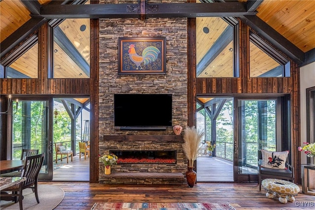 living room with high vaulted ceiling, beamed ceiling, a stone fireplace, and hardwood / wood-style floors